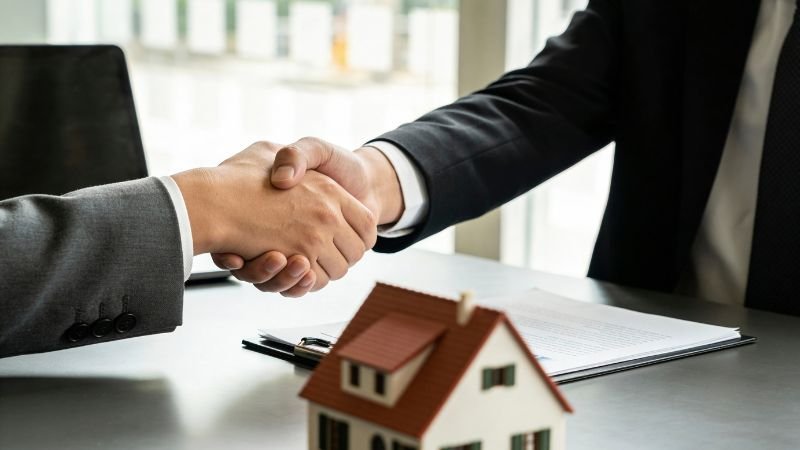 eal estate investment agreement handshake between two professionals with house model on desk
