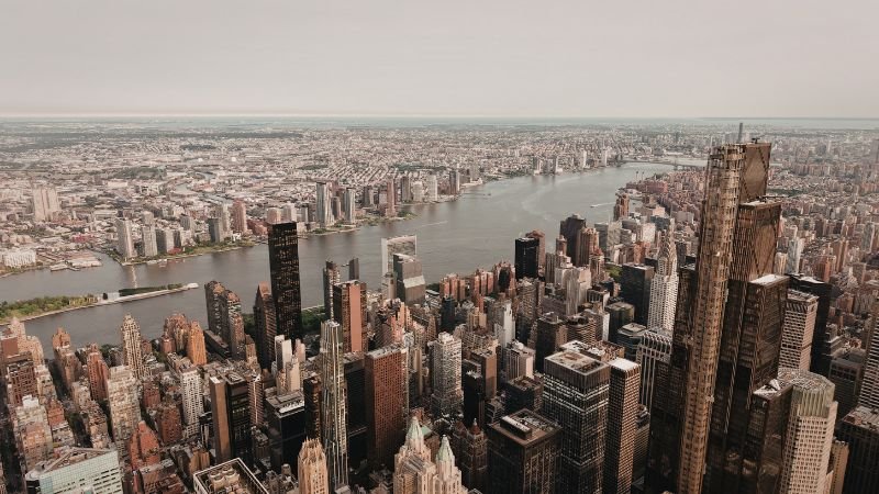 Aerial view of a dense metropolitan city skyline with high-rise buildings along a river, showcasing a prime location for real estate investment in 2026.