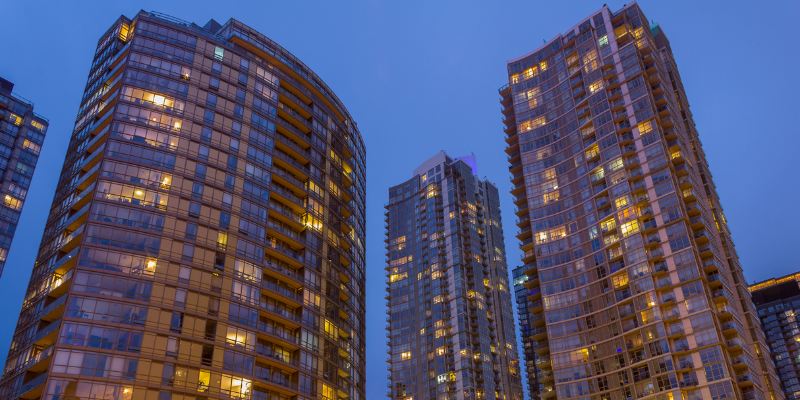 “Modern high-rise residential buildings with glass facades illuminated at dusk.”